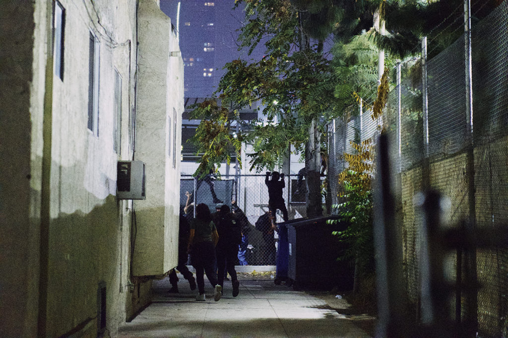 After being edged in on both sides of 18th street, protestors in Downtown LA discarded their riot gear and fled the scene by hopping fences to avoid approaching LAPD officers.