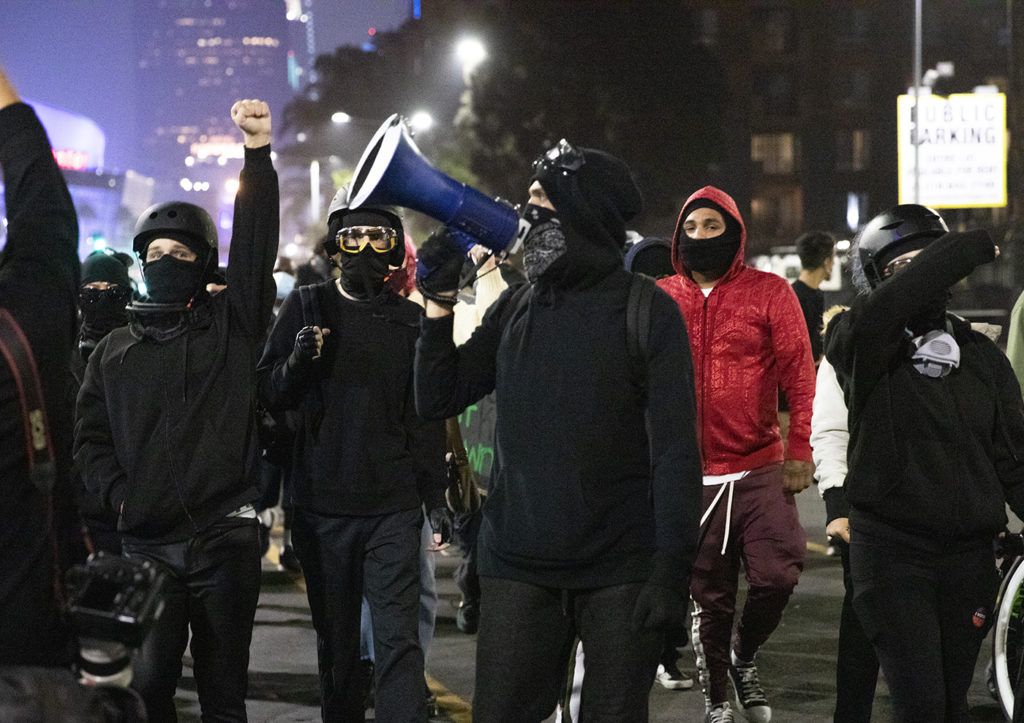 An unknown group of protestors march down S Figueroa St in downtown Los Angeles after assembling at the Staples Center while changing calls to defund the police.