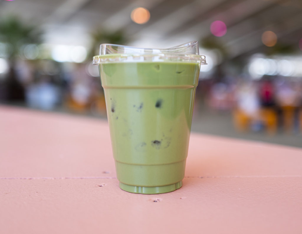 An iced matcha latte sits atop a light pink table in the Indio Central Market tent. LA-based coffee shop Dayglow offered a selection of drinks this weekend, including Greenglow, its matcha latte. (Ashley Kenney/Photo editor)