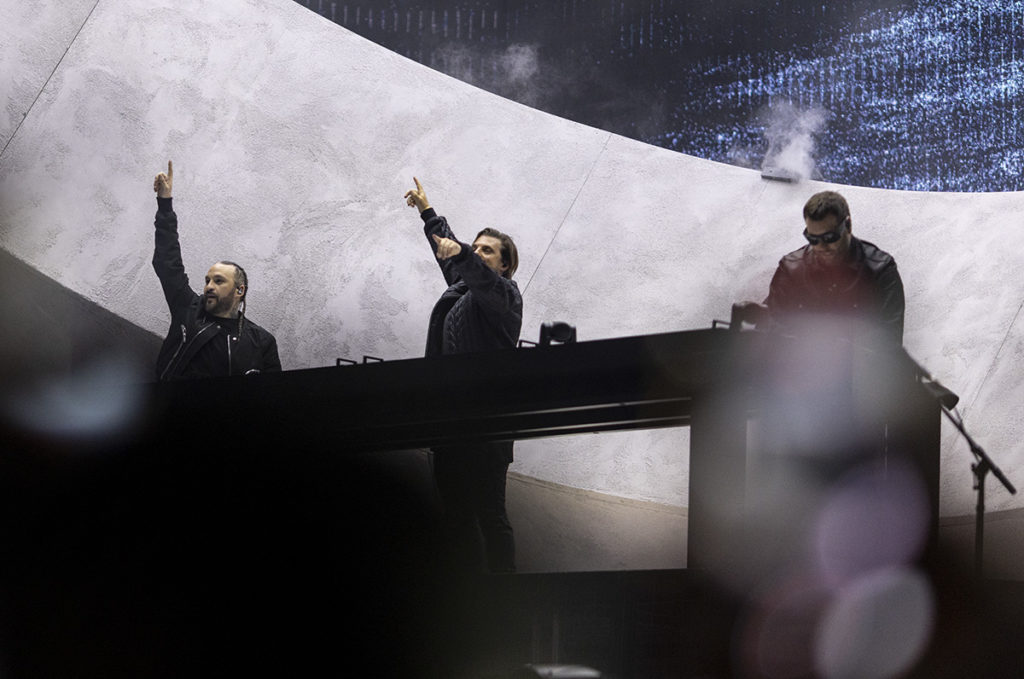 Swedish House Mafia stands together as two members point up (right) and into the crowd (center). The house music trio performed solo before melding into The Weeknd with "Sacrifice."