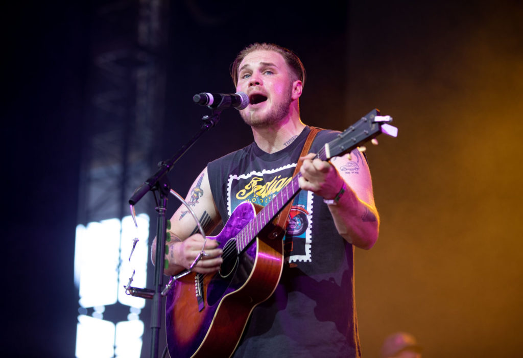 Country music artist Zach Bryan sings and plays the acoustic guitar. For his performance, Bryan highlighted the folk tones to his tracks with the help of a fiddler and upright bass player. (Anya Yakimenko/Daily Bruin)