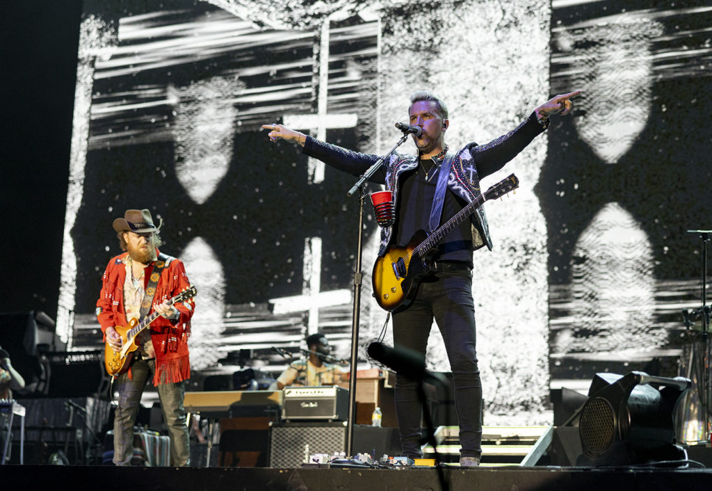 Sibling duo Brothers Osborne, composed of John (left) and TJ Osborne (right), play electric guitar and sing with arms open wide, respectively. The brothers were the second-to-last performer on the Mane Stage for Day 2, and often used bright visuals on the stage's large screen to synch up with each song's lyrics. (Anya Yakimenko/Daily Bruin)