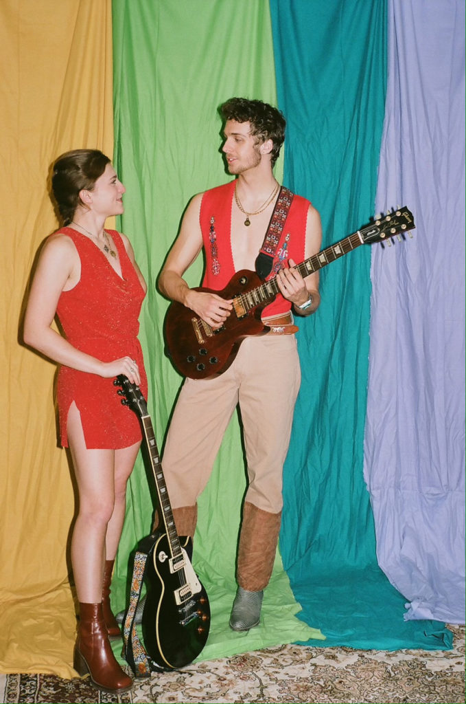 Hill (left) and Palermo (right) stand with their guitars and look at one another. For their blues-infused performance, the pair will wear '70s influenced outfits, channelling Los Angeles' Laurel Canyon. (Courtesy of Michael Palermo and Mariah Hill)