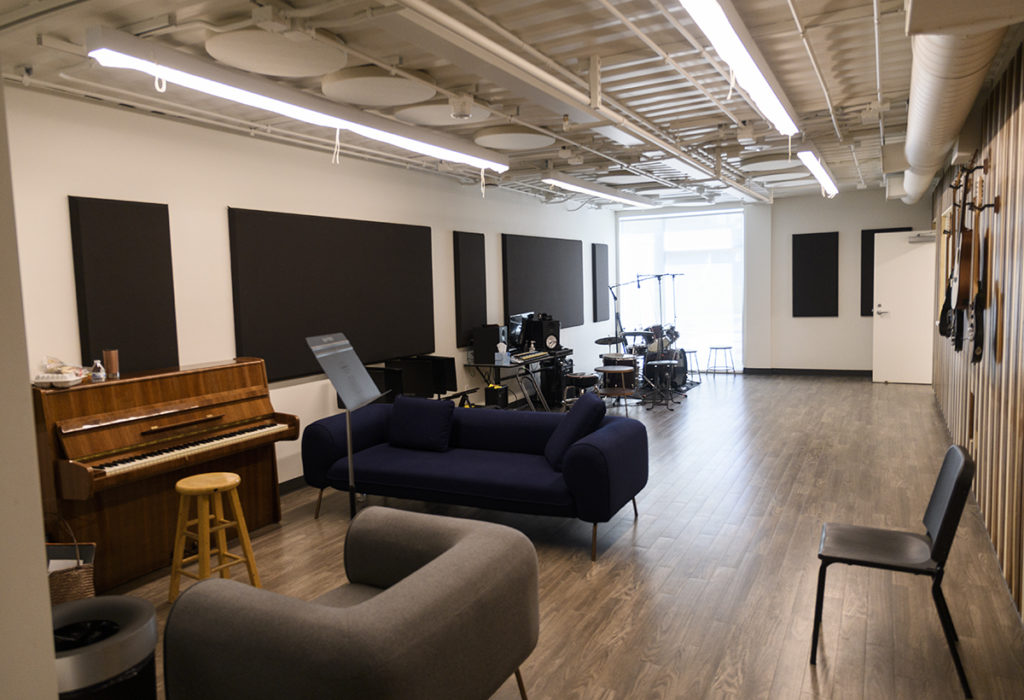 Couches, a piano, a drum set and other interactive elements are arranged in a room, continuing HOLA's light and practical design. (Kyle Kotanchek/Daily Bruin)