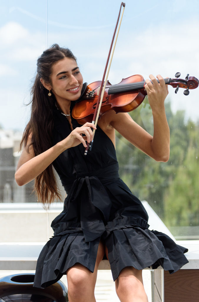 Escobar plays the violin as she sits near a window. Escobar said her original song "Jenny" serves as a message to her past self, centering on her musical aspirations at a young age. (August Suchecki/Daily Bruin)