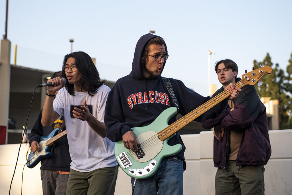 (From left to right) Third-year theater students EJ Chen, Gil Weissman and Ian Gibson practice their Spring performance as Chen sings alongside Weissman on bass as Gibson stands behind. While the group began as cover band, Chen said the group evolved into a musical collective through collaborating with artists of genres. (August Suchecki/Daily Bruin)