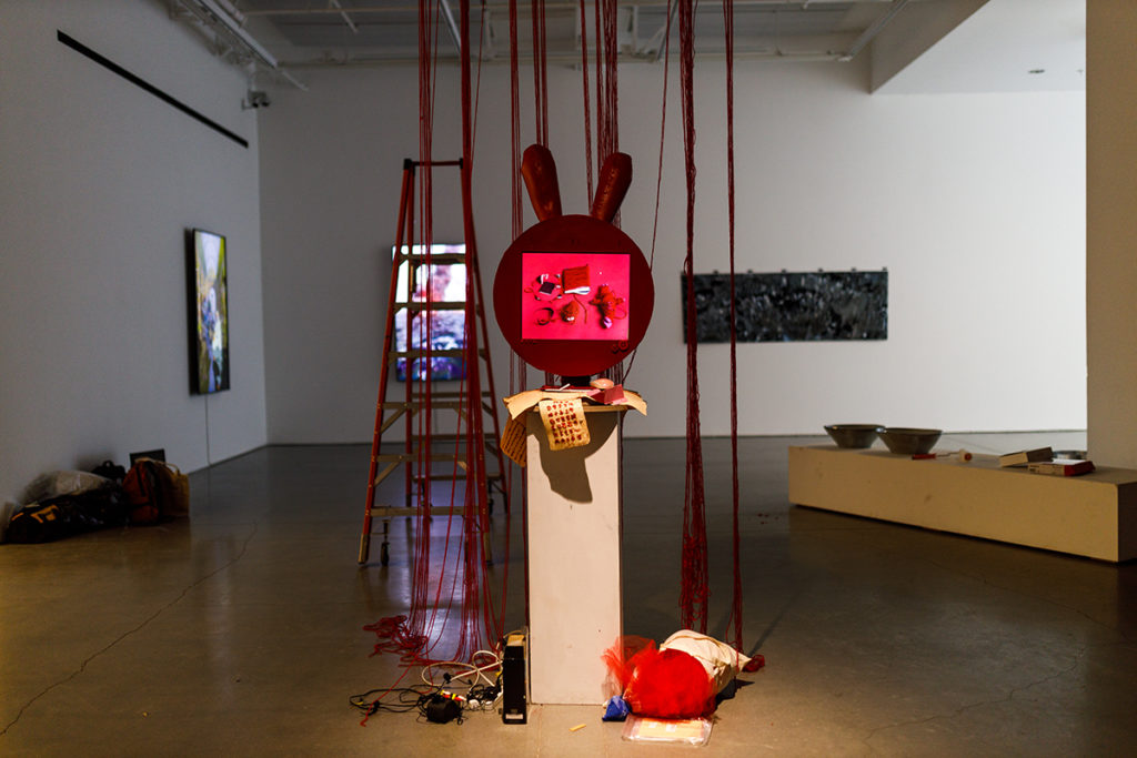 In the installing stage, Yuchi Ma&squot;s piece "Red Thread (我很爱你)" features elements such as dangling red threads and video screen wrapped with a red bunny cover. Ma said the pedestal on which the video and bunny structure rests will have fake skin with tattoos of Tang dynasty poem "游子吟 (Song of the Wanderer)" on it. (Shengfeng Chien/Daily Bruin)