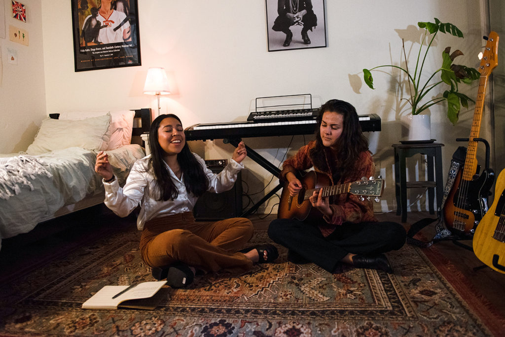 Silva (left) sings in a bedroom as Bettendorf (right) sits beside her playing guitar. At Spring Sing, the band will debut its new song "We Can Dance" with funk-pop with R&B influences. (Jefferson Alade/Daily Bruin)