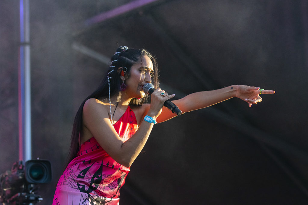 Raveena points to out to crowd during her early evening set. The soul pop singer was frequently illuminated by pink and magenta lights from the psychedelic visuals displayed on the screen behind her. (Megan Cai/Assistant Photo editor)
