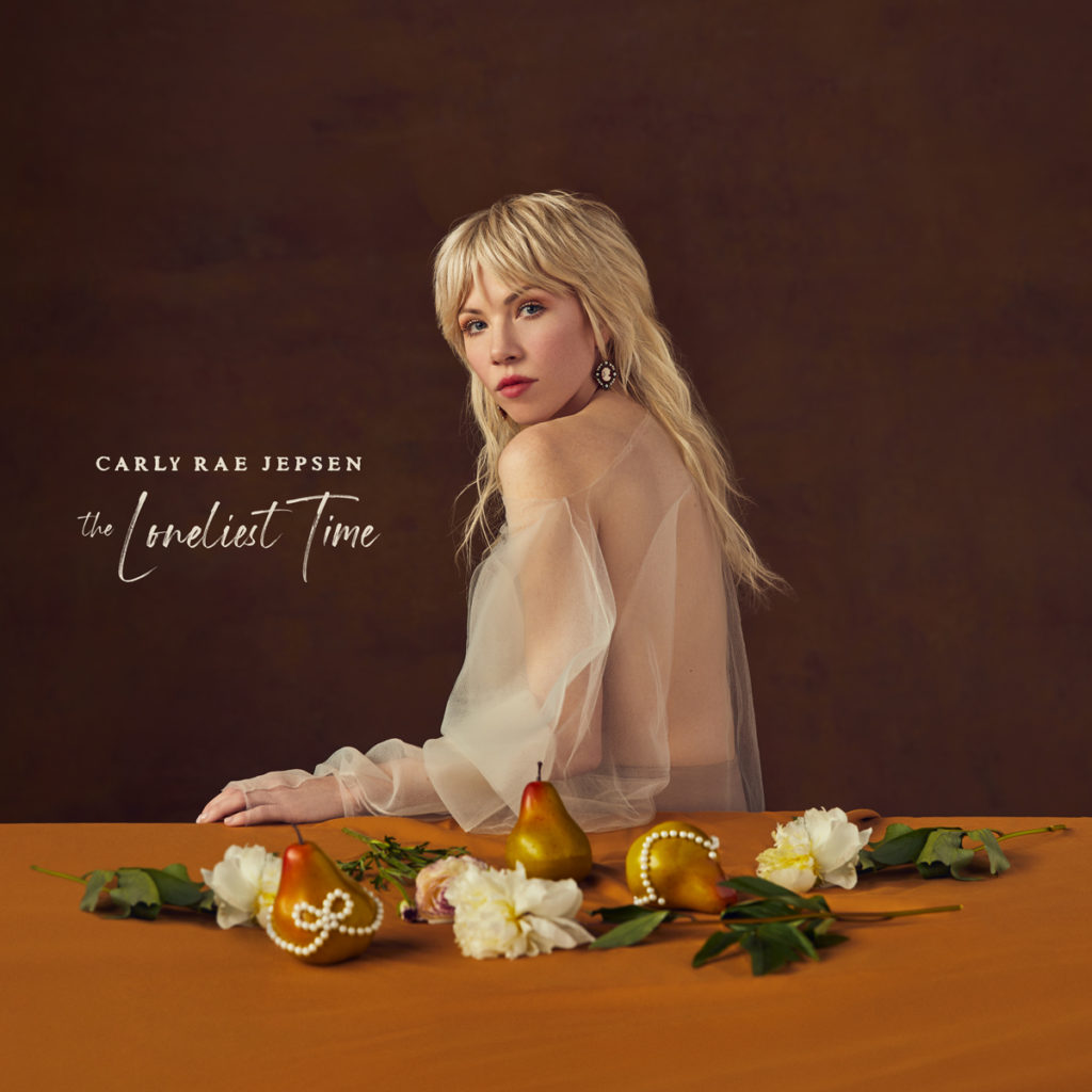 Set to drop Oct. 21, the warm-toned cover for Carly Rae Jepsen&squot;s "The Loneliest Time" features the singer alongside decorative fruit. (Courtesy of Interscope Records)