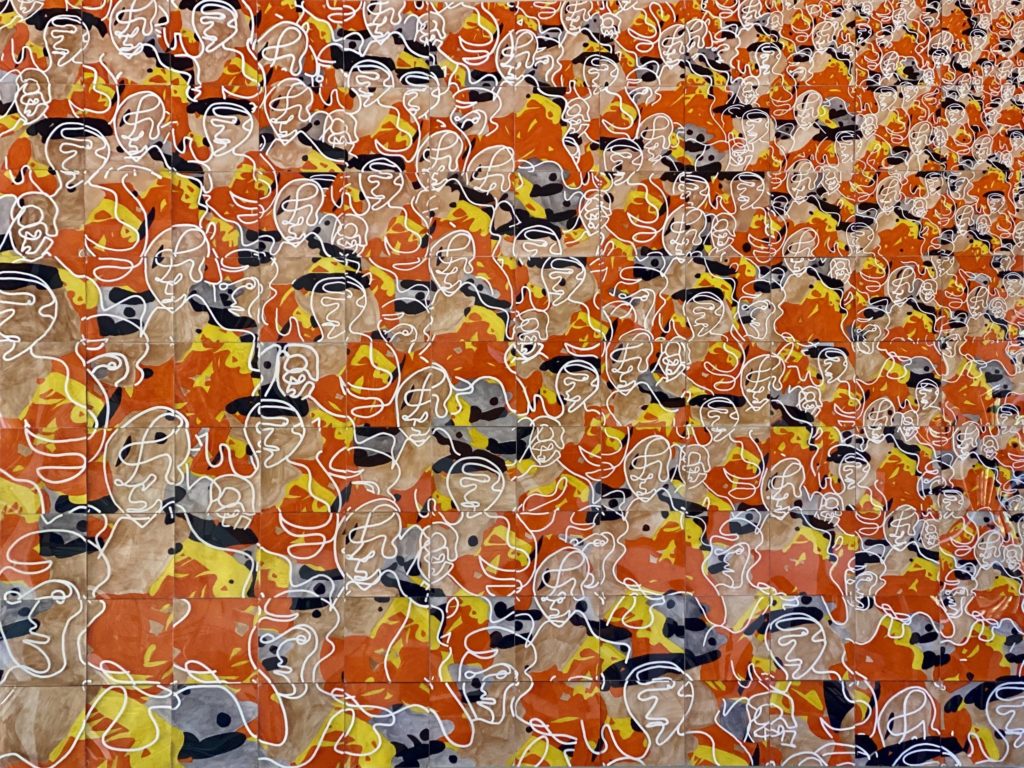 Abstract faces surrounded by marbled orange and yellow serve make up "Be Unique." The painting which Baldwin said was one of his first large-scale works features layers of plexiglass to provide depth and texture. (Courtesy of Henry Baldwin)