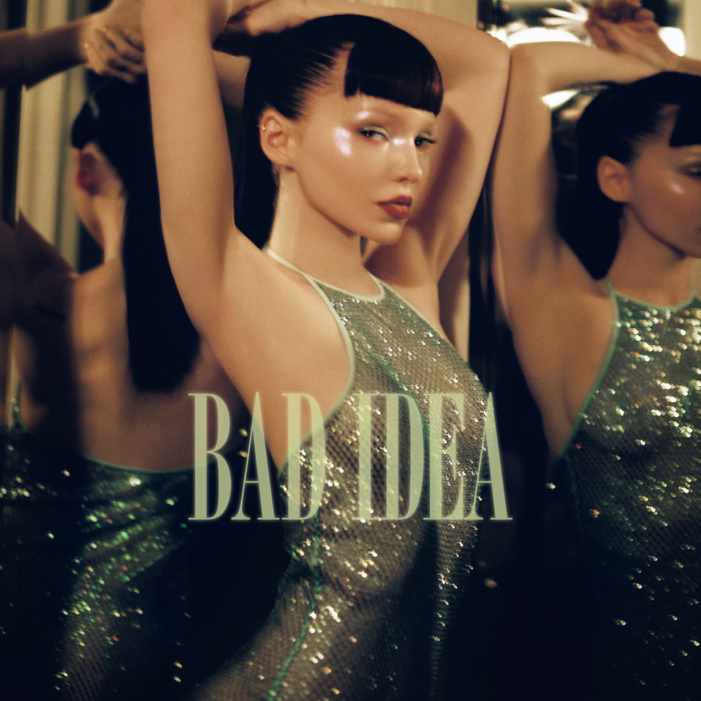 Surrounded by mirrors, Dove Cameron wears glowing makeup and a shimmering green dress on the cover of her latest single, "Bad Idea." (Courtesy of Columbia Records)