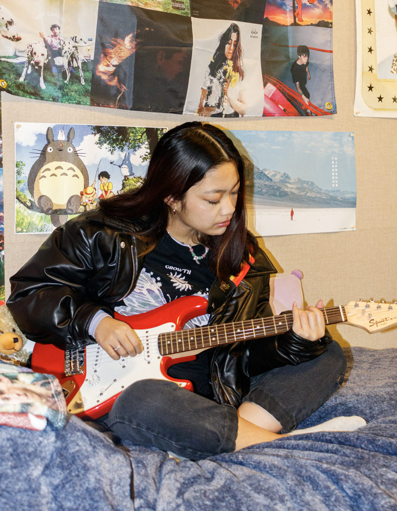 Marcelo looks down as she plays a red and white guitar. Marcelo said her tracks aim to explore themes ranging from love, isolation and growing older. (Eden Yu/Daily Bruin)