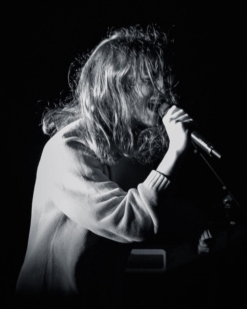 Electro-pop singer and instrumentalist brakence sings into a microphone in a black and white photo. (Courtesy of Sydney Wright)