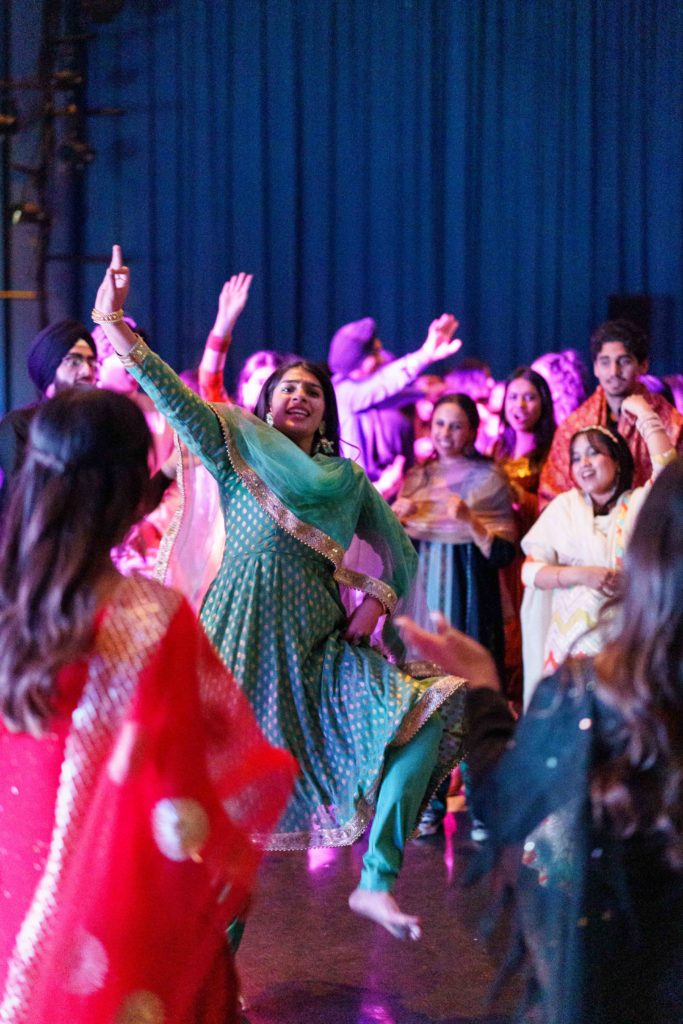 Attendees cheer on a dancer dressed in gold and green. In addition to food and an open dance floor, the event featured performances of traditional Punjabi dances by various dance teams including UCLA's Bhangra team. (Brandon Morquecho/Daily Bruin)
