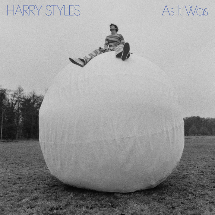 In black and white, Harry Styles sits on a white ball on the single cover for his pop track "As It Was" (Courtesy of Columbia Records)