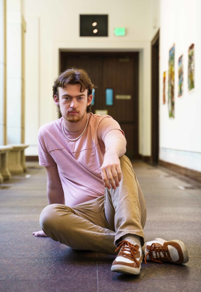 Strachan sits in a hallway. The artist will perform his original song "No Strings" when he competes at this year&squot;s Spring Sing. (Halinda Yu/Daily Bruin)