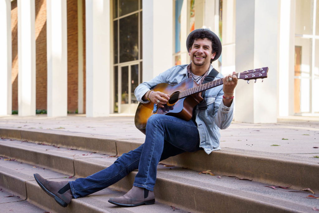 Lopez sits on steps outside while playing his guitar. The vocalist and instrumentalist will perform his song "Mírame" when competes at Spring Sing Friday. (Julia Zhou/Daily Bruin)