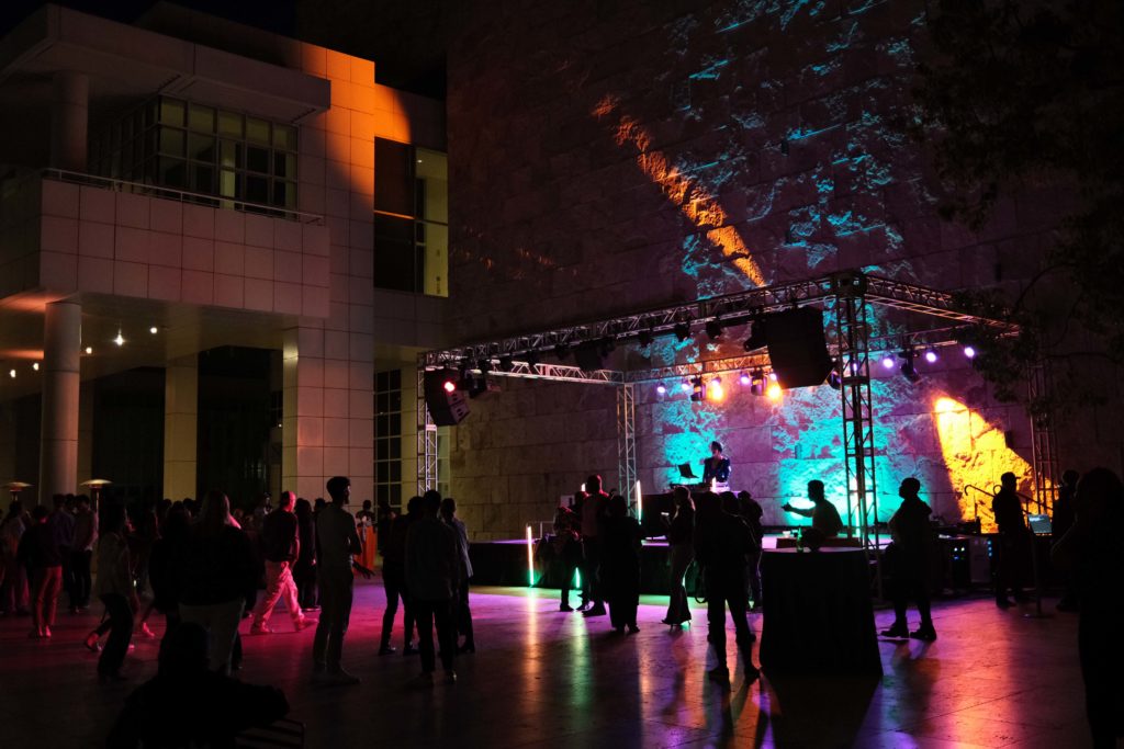 Attendees gather around an outdoor stage as lights color the museum's courtyard with the full spectrum of the rainbow. Following the hour-long talk, the Getty Center hosted an after party with live music from DJ Daisy O’Dell. (Shengfeng Chien/Daily Bruin staff)