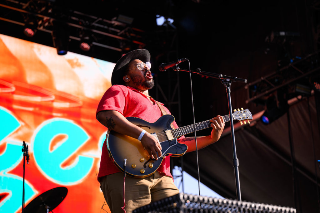 Day two opener Bartees Strange stands at his mic stand in front of a cyan and orange digital display. Strange opened with "Far" while sporting a black cowboy hat and red shirt. (Anika Chakrabarti/Photo editor)