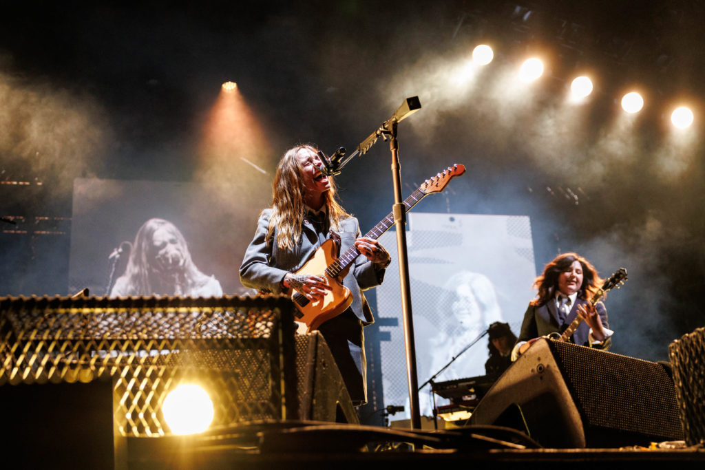 Under the glow of golden lights, Phoebe Bridgers (left) sings into the mic whilst holding a guitar. Bridgers and fellow boygenius bandmates Julien Baker (center) and Lucy Dacus (right) performed a solo song in addition to tracks from the group's discography. (Anika Chakrabarti/Photo editor)