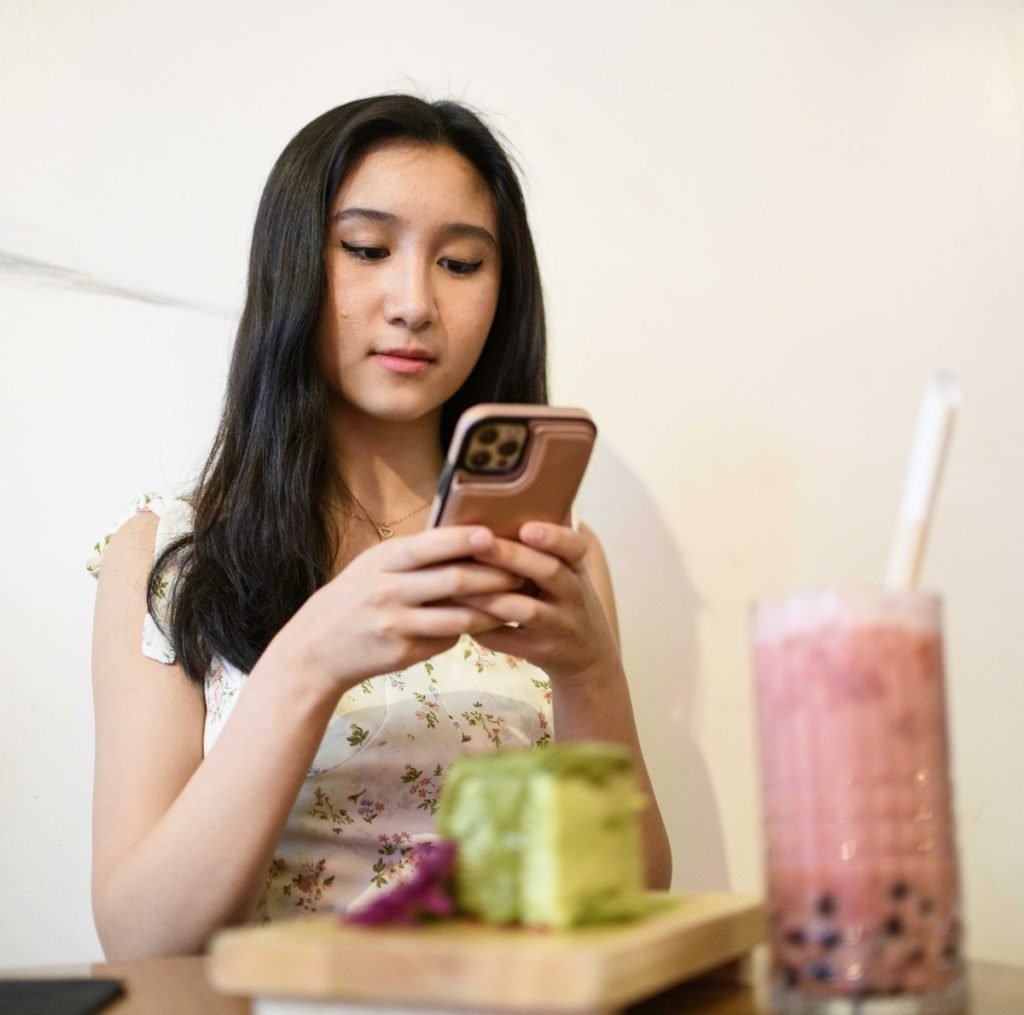 Teng gets ready to take a photo of her food. With her account growing to over 3,000 followers, she said she has received various brand partnerships. (Photo by Jeremy Chen/Daily Bruin senior staff. Photo illustration by Ashley Ko/Illustrations Director)