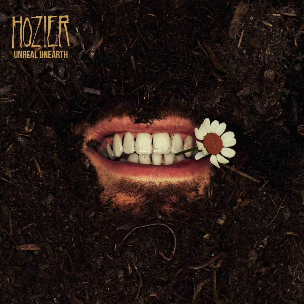 Buried under mulch and dirt, a mouth clenches a flower between its teeth. Hozier&squot;s "Unreal Unearth" will release on August 18. (Courtesy of Columbia)