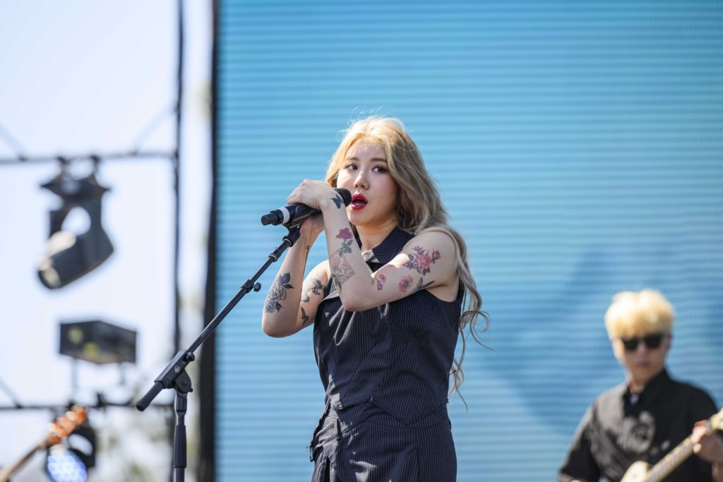 Yerin Baek grips the microphone with her florally-tattooed arms. The South Korean musician serenaded the afternoon crowd with her vocals and an unreleased song. (Megan Cai/Daily Bruin senior staff)