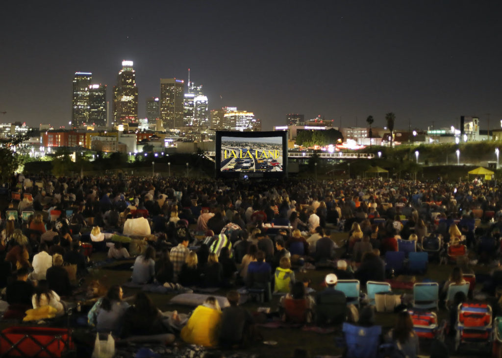 Amid the backdrop of the city skyline, picnicgoers watch a nighttime screening of "La La Land." Released in 2016, the film won six Academy Awards including Best Original Score. (Courtesy of Street Food Cinema)
