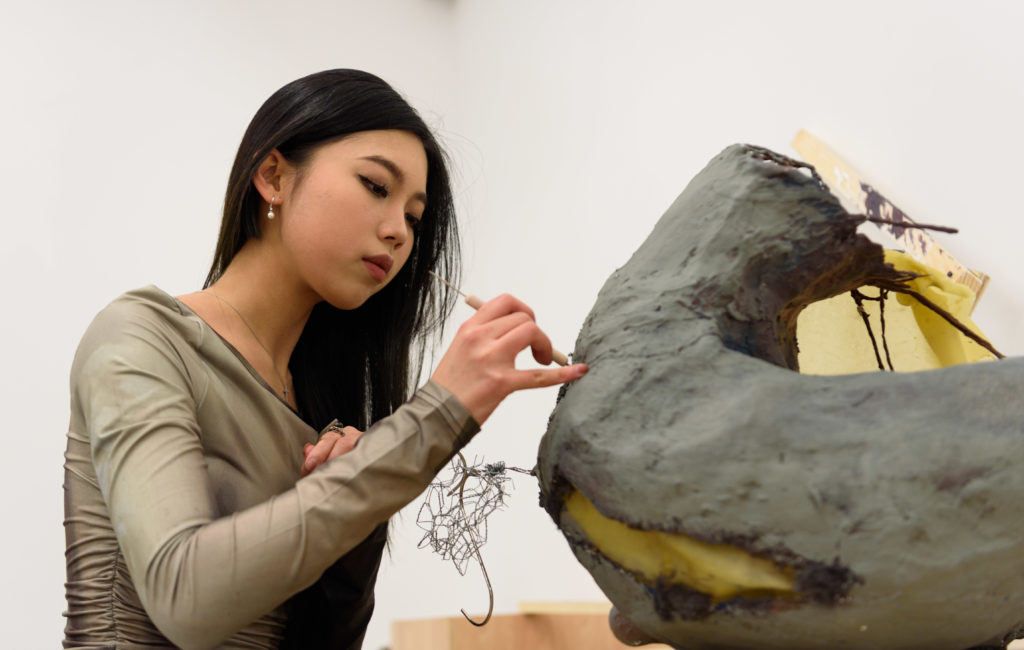 Li uses a sculpting tool to mold the exterior of her piece. An international student, Li said her unique perspective made her realize the need for empathy-generating art. (Nicolas Greamo/Daily Bruin senior staff)