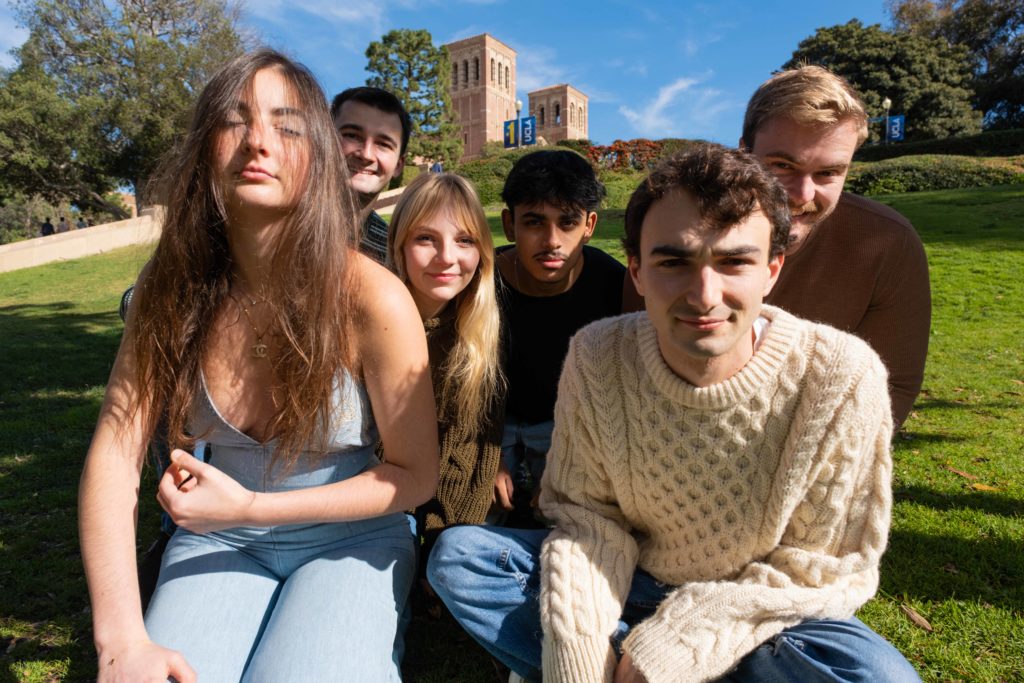 The bandmates huddle together on the greenery of the UCLA campus. Music history and industry alumnus Jack Zager said the group strives to use the opportunities presented by attending the university. (Aidan Sun/Daily Bruin)
