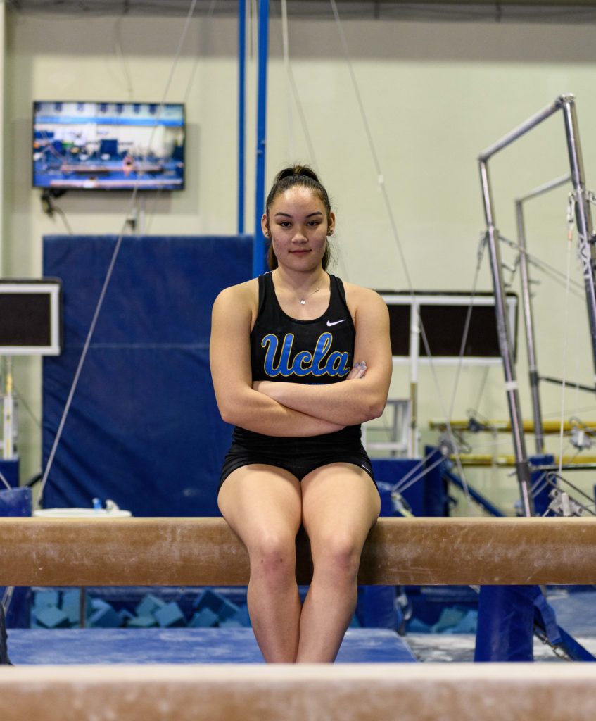 Alipio sits on the balance beam at Yates Gym in the John Wooden Center. (Ella Greenberg Winnick/Daily Bruin staff)