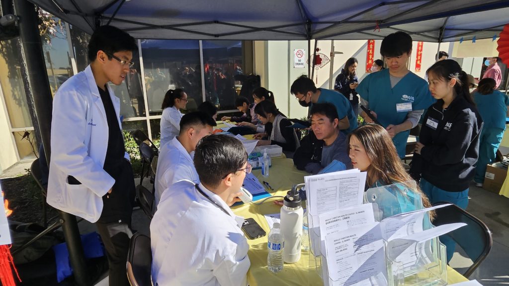 Volunteers at the health fair sit around a table. Undergraduate volunteers from APA Health Care served as client navigators to help bridge the gap and act as a translator, if necessary, between patients and medical students. (Courtesy of Jim Su)