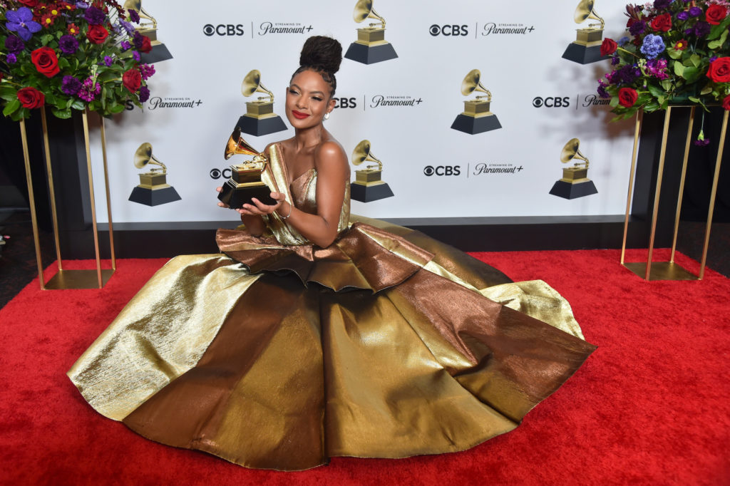 Kneeling in a golden gown, Allison Russell holds her first Grammy award, which she won in the Best Americana Album category for "The Returner." Released in September, the album touches on themes of Black liberation, love and self-respect. (Courtesy of Alberto E. Rodriguez/Getty Images for The Recording Academy)