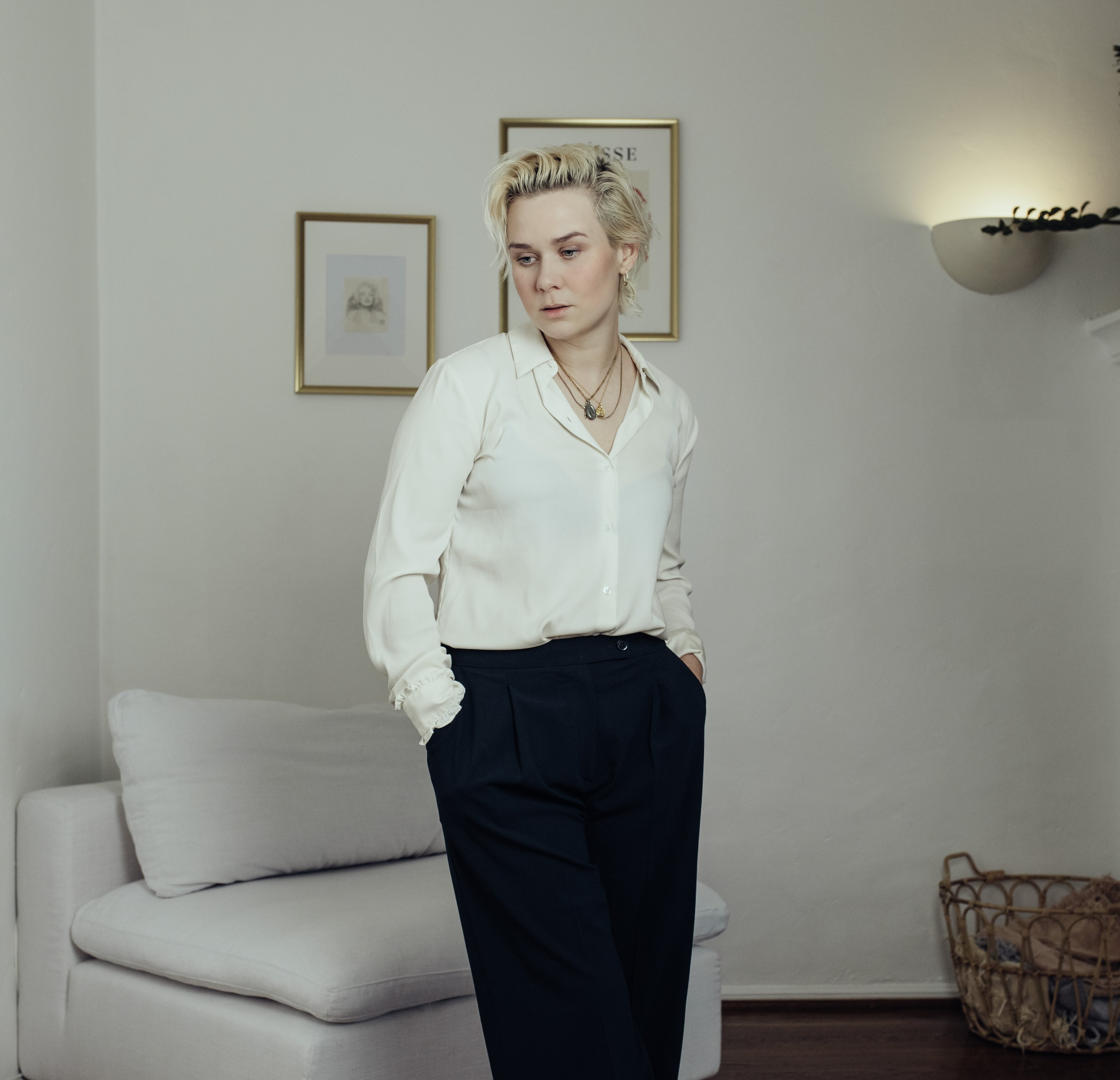 Amy Kuney stands in a monochromatic white room while wearing a white blouse and black pants. The songwriting lecturer said she has been working in the music industry in Los Angeles for more than 20 years, and is excited to see more queer anthems -- like the music created by Chappell Roan -- become successful. (Courtesy of Alexandra Petruck)