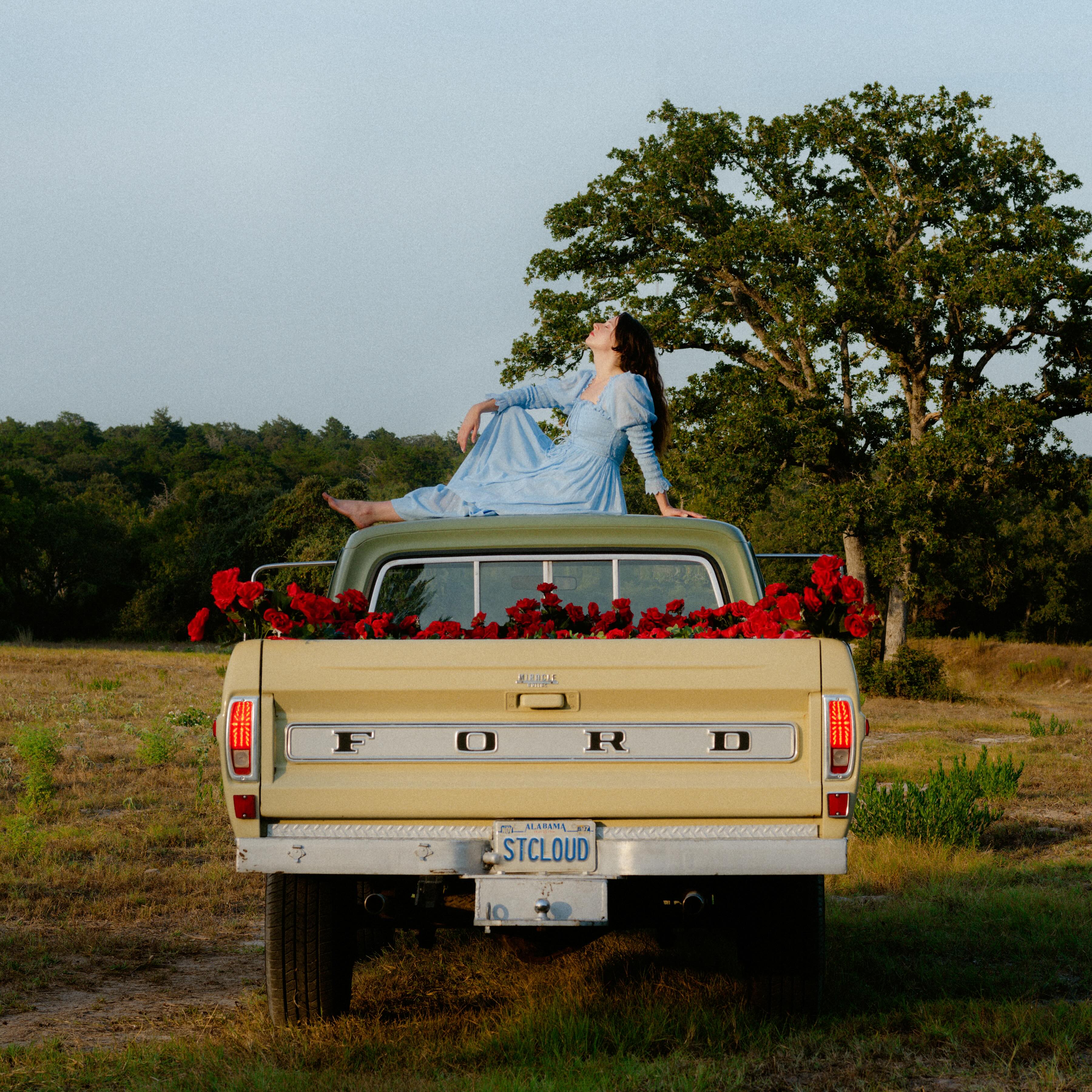 Katie Crutchfield sits atop a yellow Ford truck with a truck bed full of roses while wearing a blue dress and parked in a grassy field on the cover of Waxahatchee&squot;s 2020 album "Saint Cloud." Crutchfield is the leader of the indie rock act, and "Saint Cloud" includes the song "Can&squot;t Do Much." (Courtesy of Merge Records)