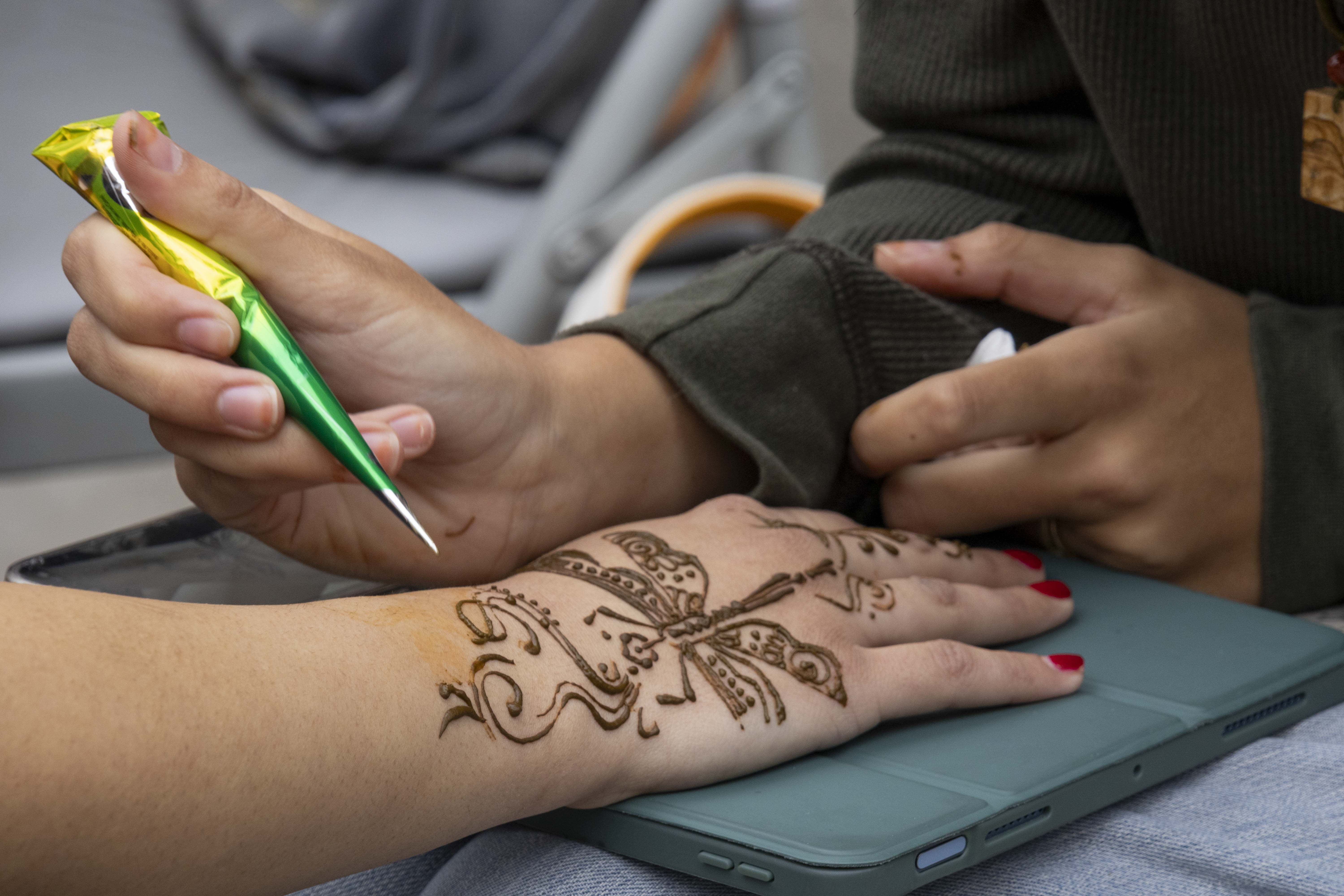 A person draws a henna design on a hand. The flea market saw vendors who brought activities and clothing for the event. (Selin Filiz/Daily Bruin)