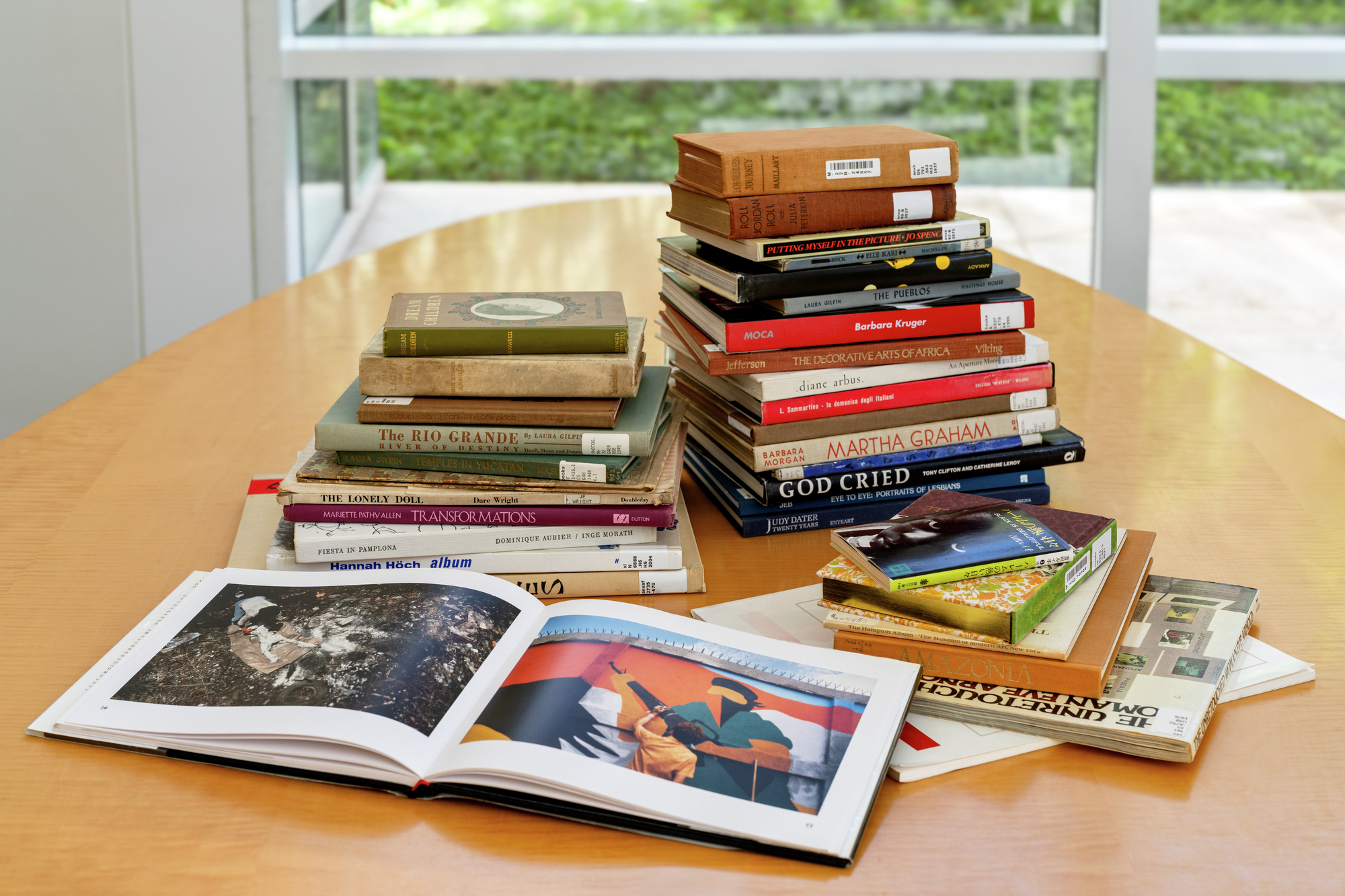 A few short stacks of books referenced in the Getty Center exhibition "What They Saw: Historical Photobooks by Women, 1843-1999" rest on a golden-brown table. The exhibition, which debuted April 8, is on view to the public until May 11. (Courtesy of J. Paul Getty Trust)