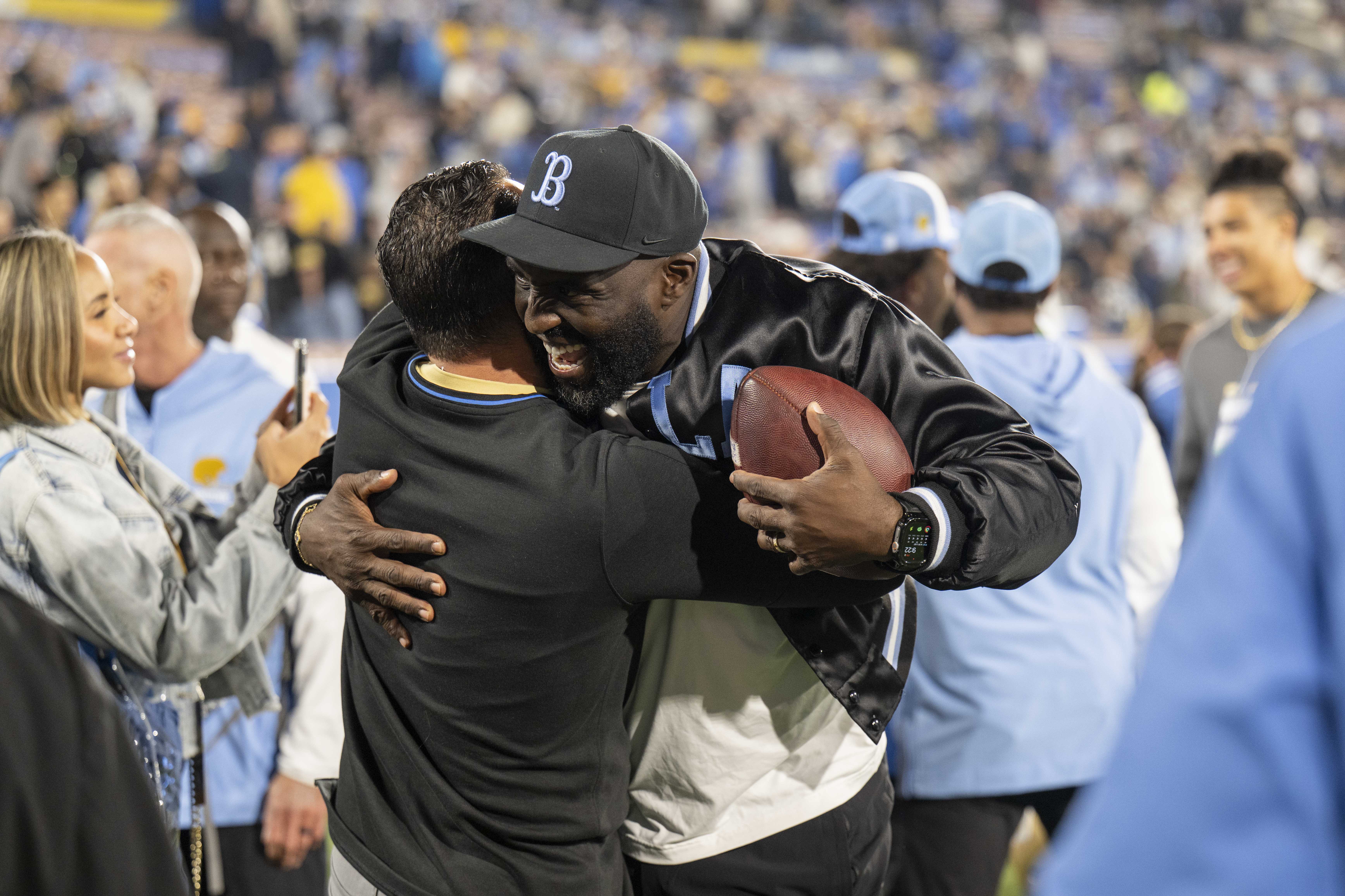 Coach DeShaun Foster hugs someone while holding the game ball after a win. (Nicolas Greamo/Daily Bruin senior staff)
