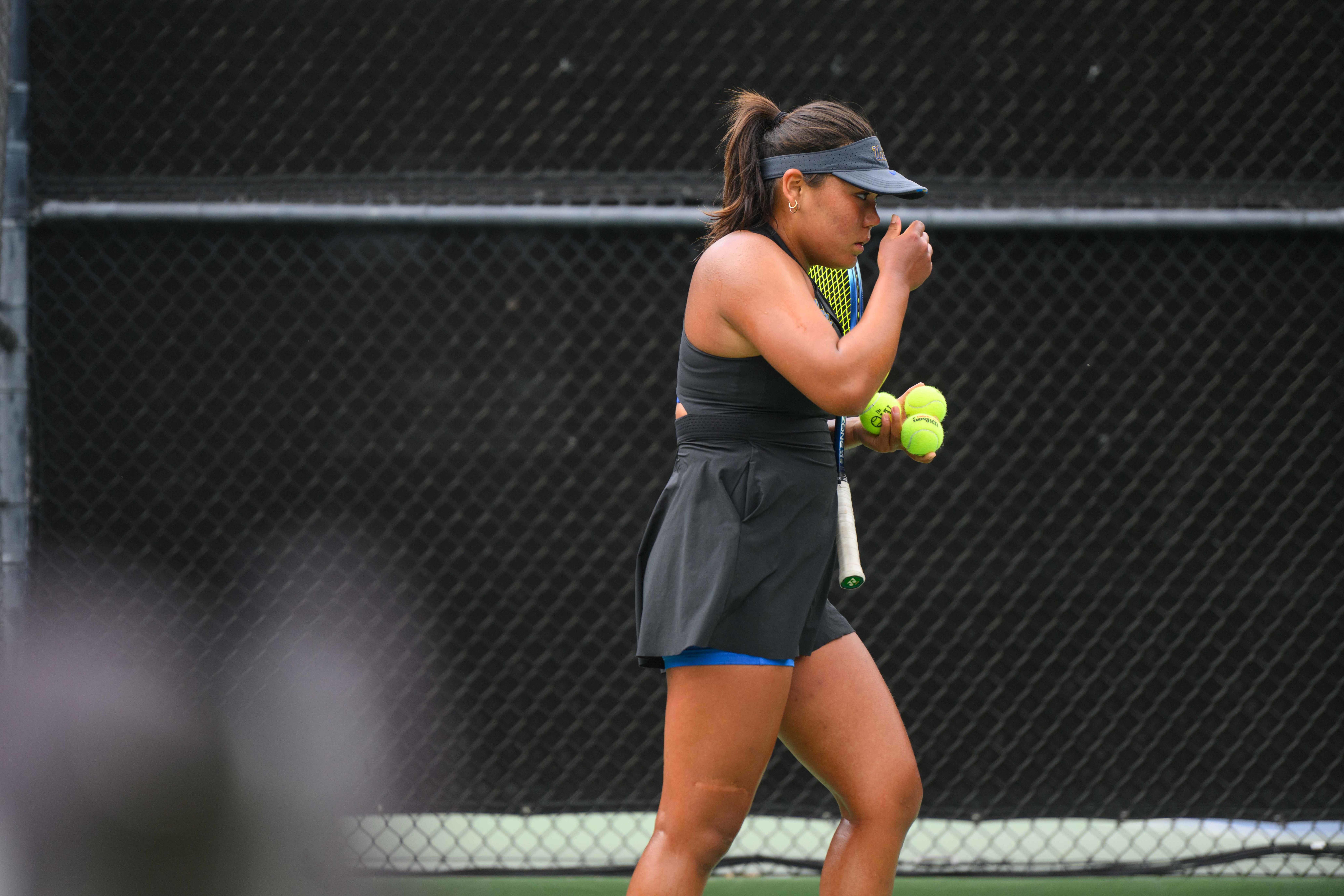 No. 39 freshman Kate Fakih covers her face as she walks across the court with three tennis balls and her racket in hand. (Brianna Carlson/Daily Bruin staff)