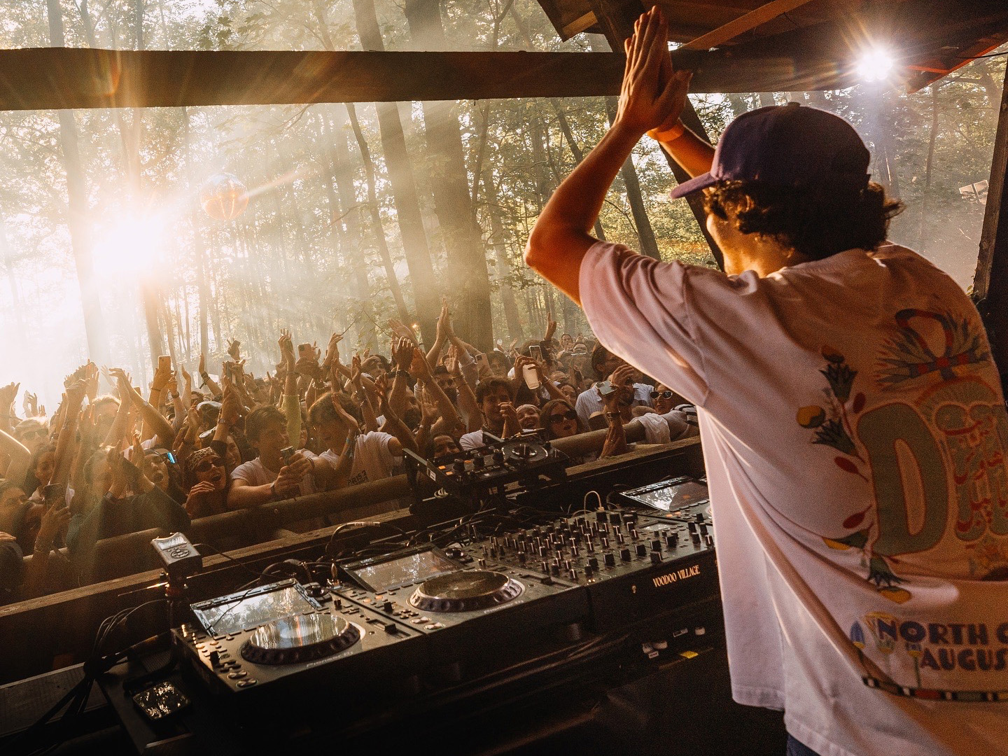 Ahmed Spins looks out toward the crowd while performing at a venue surrounded by tall trees. The producer was born in Casablanca, Morocco but studied finance at Northeastern University in Boston before pursuing a career in music full-time. (Courtesy of Kamil Kwiatkowski and Unfolded PR)