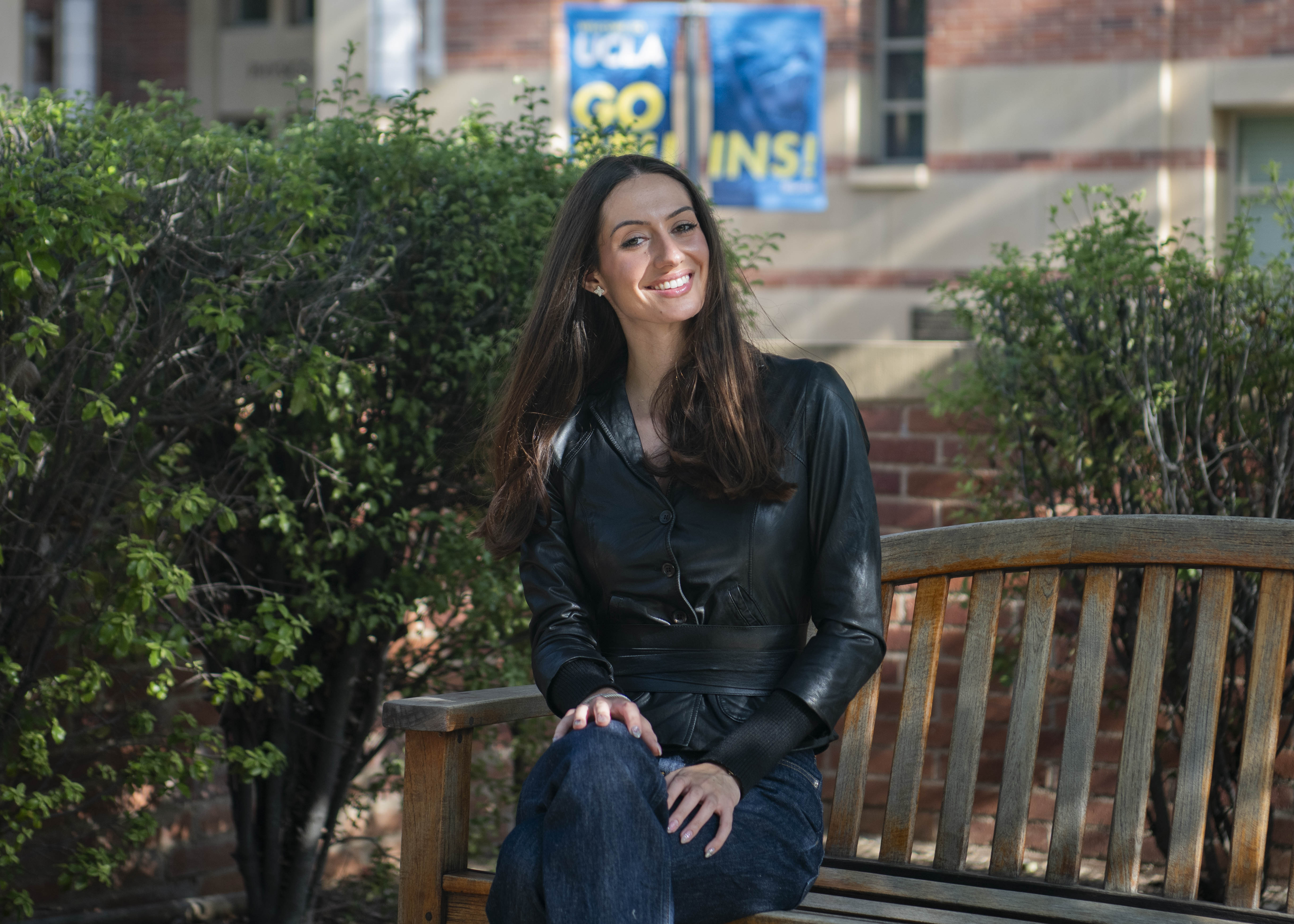 Elena Flauto sits on a wooden bench and crosses her legs while smiling for a photo. As a musician and artist herself, Flauto said her personal experiences have influenced her approach to running Cherry Pop Records and influenced her interest in pursuing a career in entertainment law. (Max Zhang/Daily Bruin)