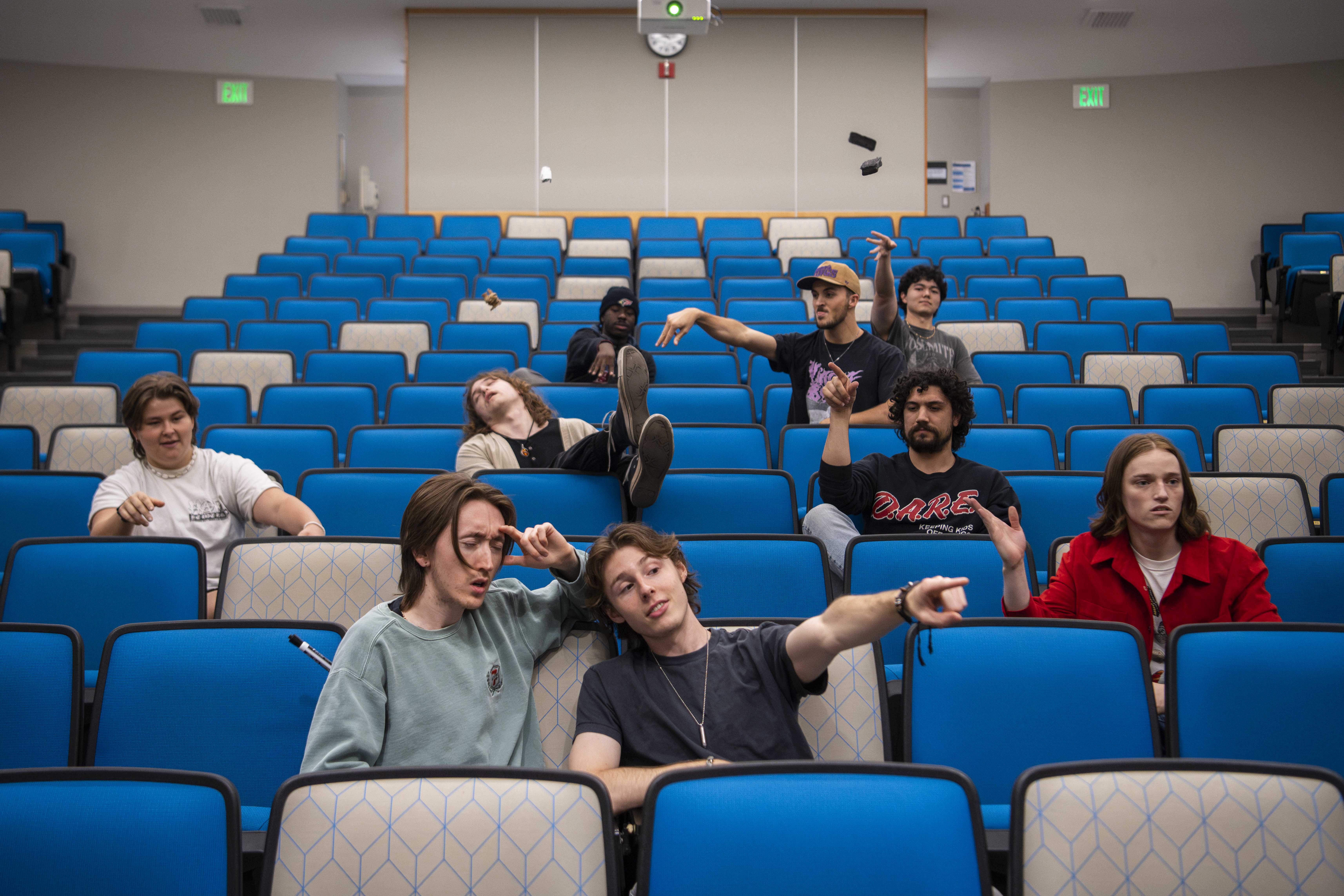 Members of The Band Called Sex are pictured sitting in an empty lecture hall with blue and white seats. The band was formed in 2020, but Ben Whitley, a fourth-year aerospace engineering student, is the only core member still enrolled at UCLA. (Ruby Galbraith/Daily Bruin)
