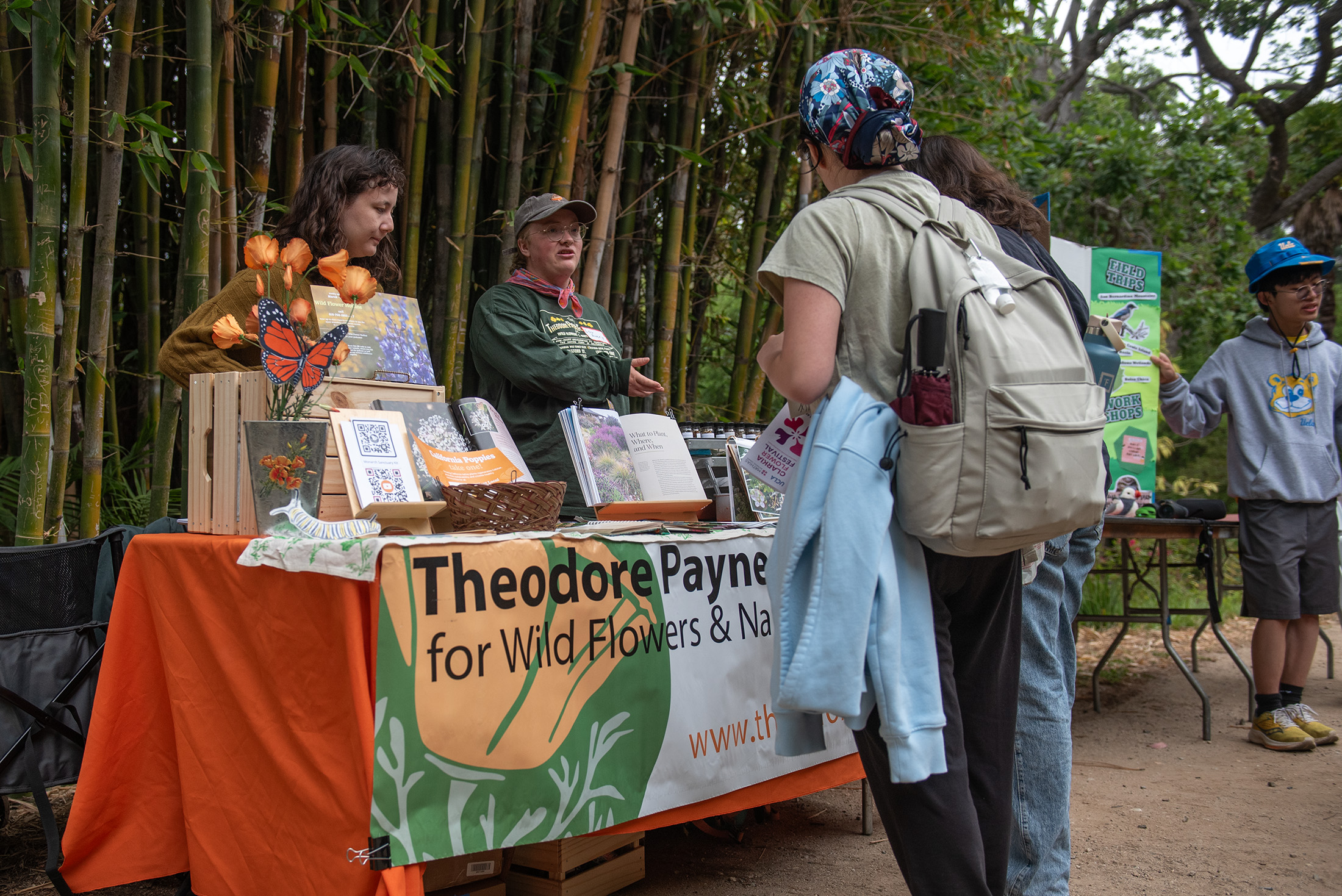 Representatives from the Theodore Payne Foundation speak with attendees at the Clarkia Flower Festival. More than 20 community and environmental organizations tabled at the May 17 event. (Max Zhang/Daily Bruin)