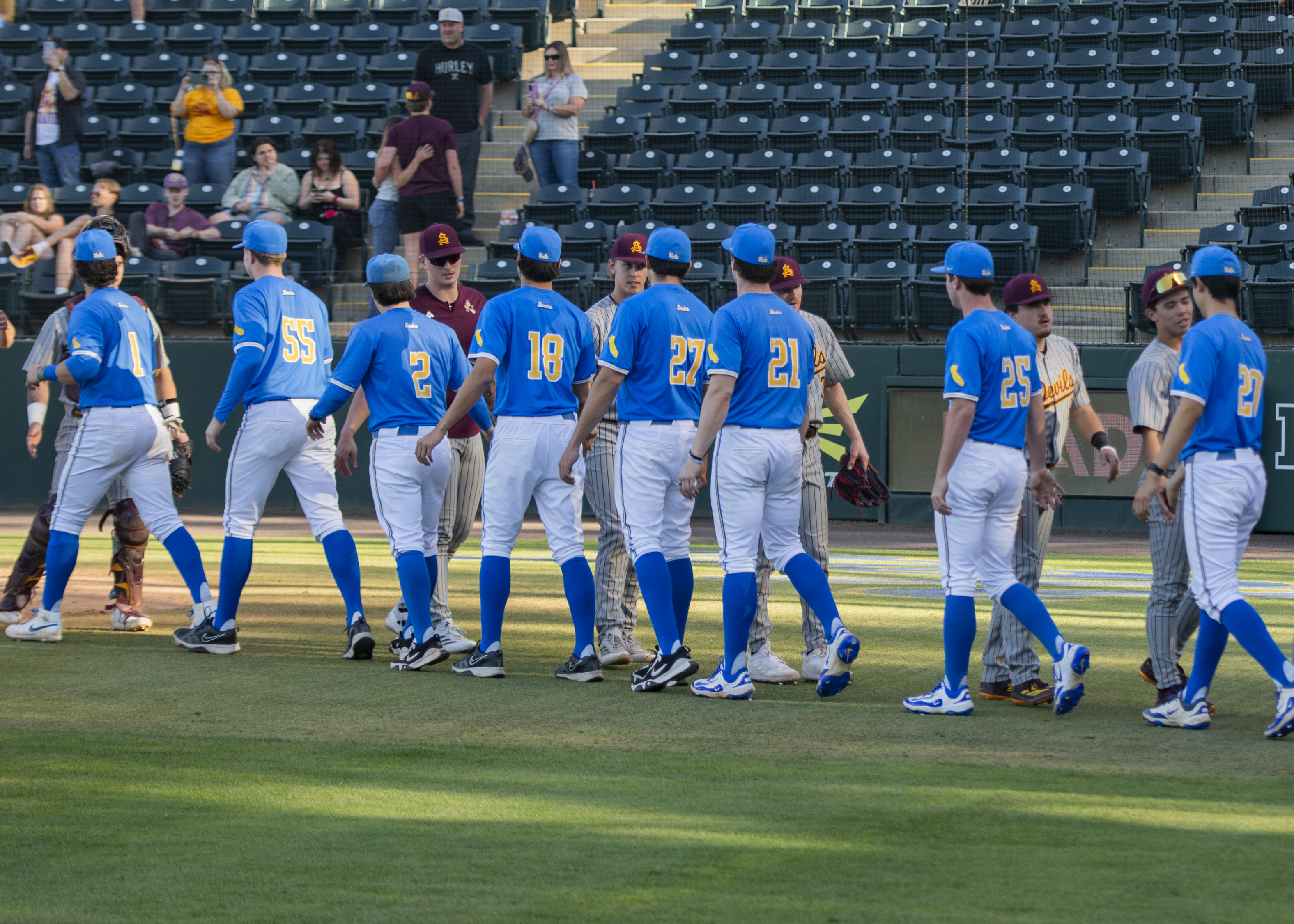 Members of UCLA baseball and Arizona State exchange high fives behind home plate. (Rylan Riccabona/Daily Bruin)