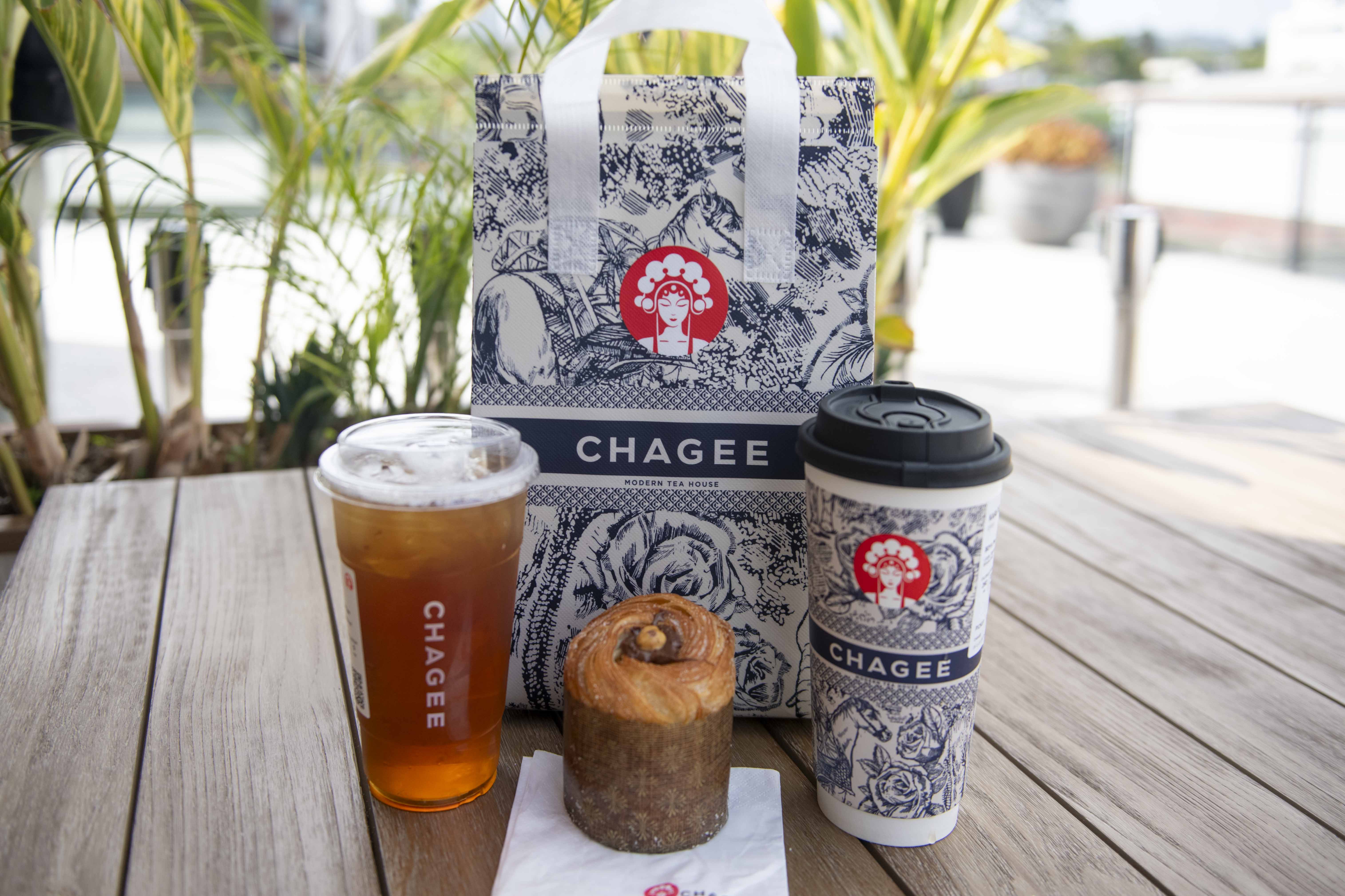 Photographed is a reusable bag, two drinks and a pastry item from CHAGEE. For their grand opening, the menu for the Century City location was reduced to four drinks and one pastry. (Karla Cardenas-Felipe/Daily Bruin staff)