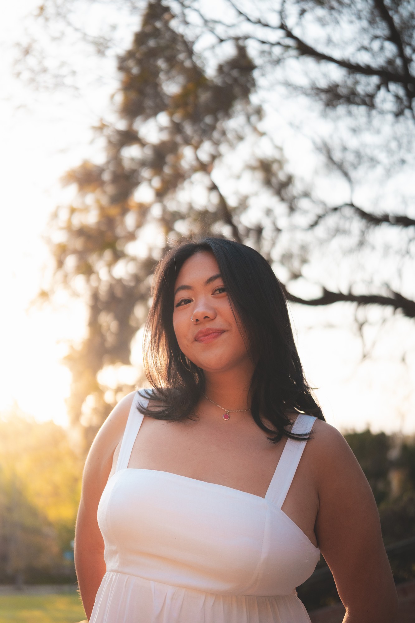 Sheng Chang looks at the camera while standing in front of trees and wearing a white top. The student musician and singer-songwriter said her artistic influences include Taylor Swift, Lizzy McAlpine and Tiny Habits. (Courtesy of Ming Vang)
