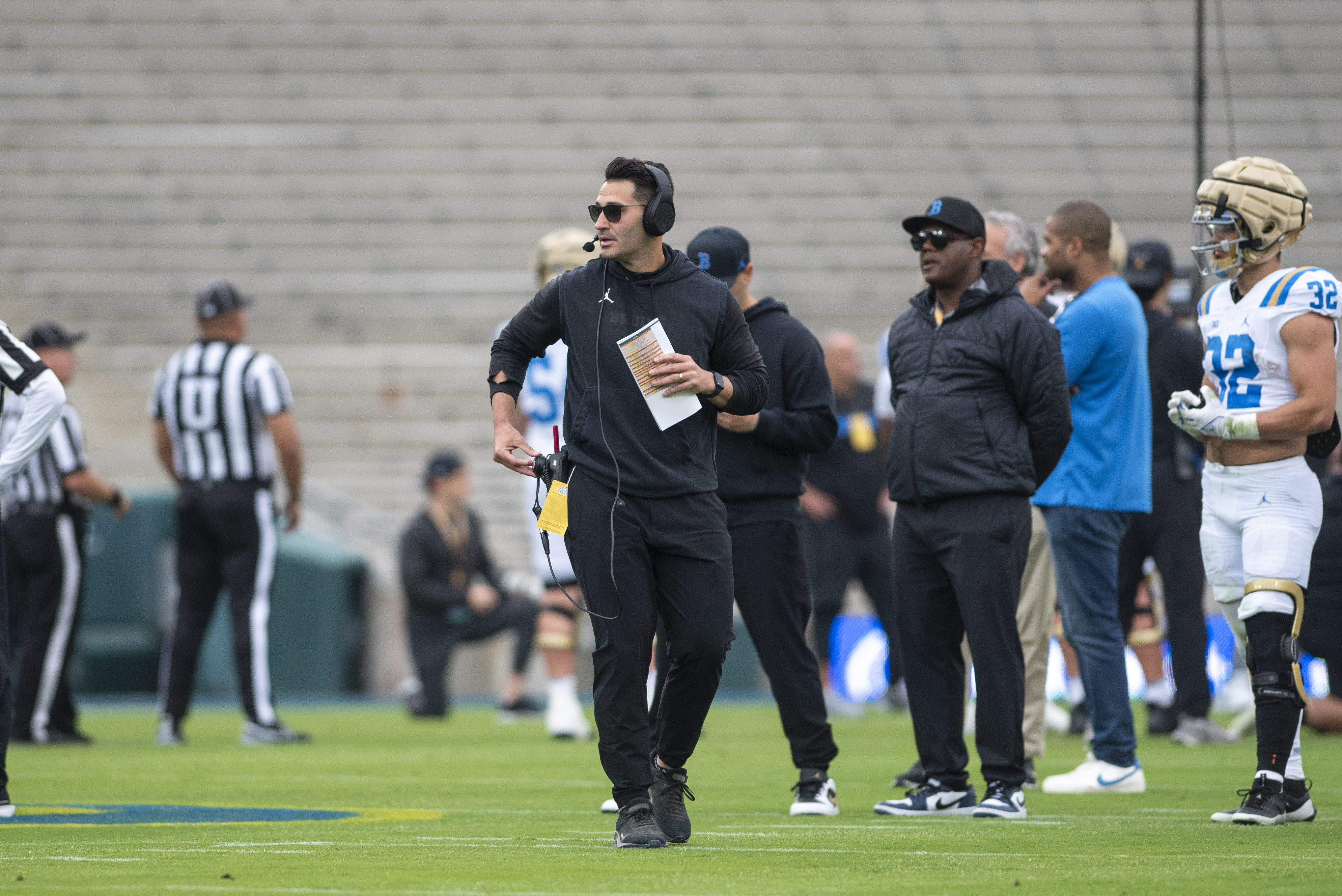 Offensive coordinator and quarterbacks coach Tino Sunseri holds UCLA's playbook and looks out at the field. (Max Zhang/Daily Bruin)