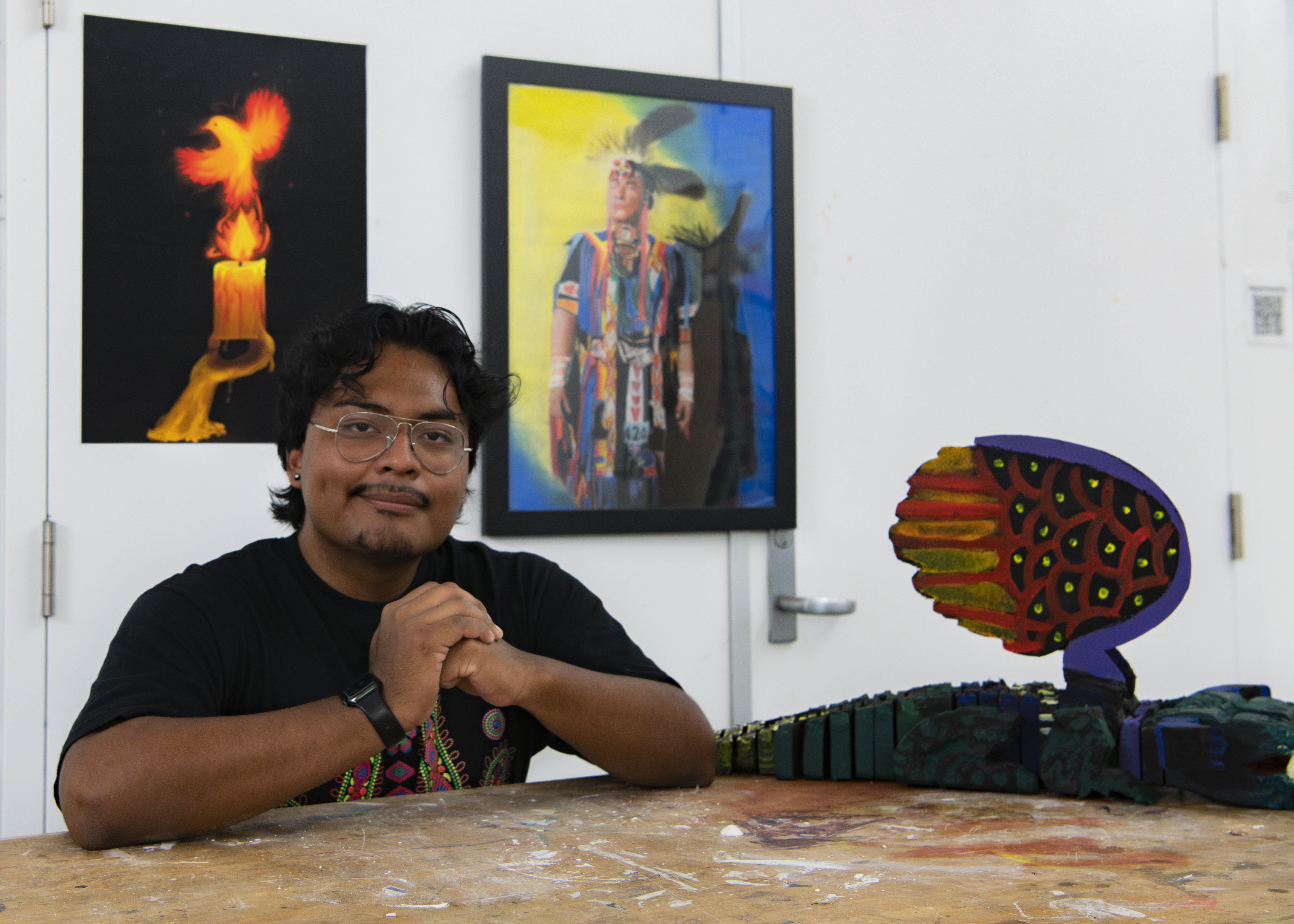 Ramirez leans over a work table while surrounded by art pieces. The student said after being able to exhibit his work in different venues, he aspires to showcase his art on a larger scale. (Isabella Appell/Daily Bruin)