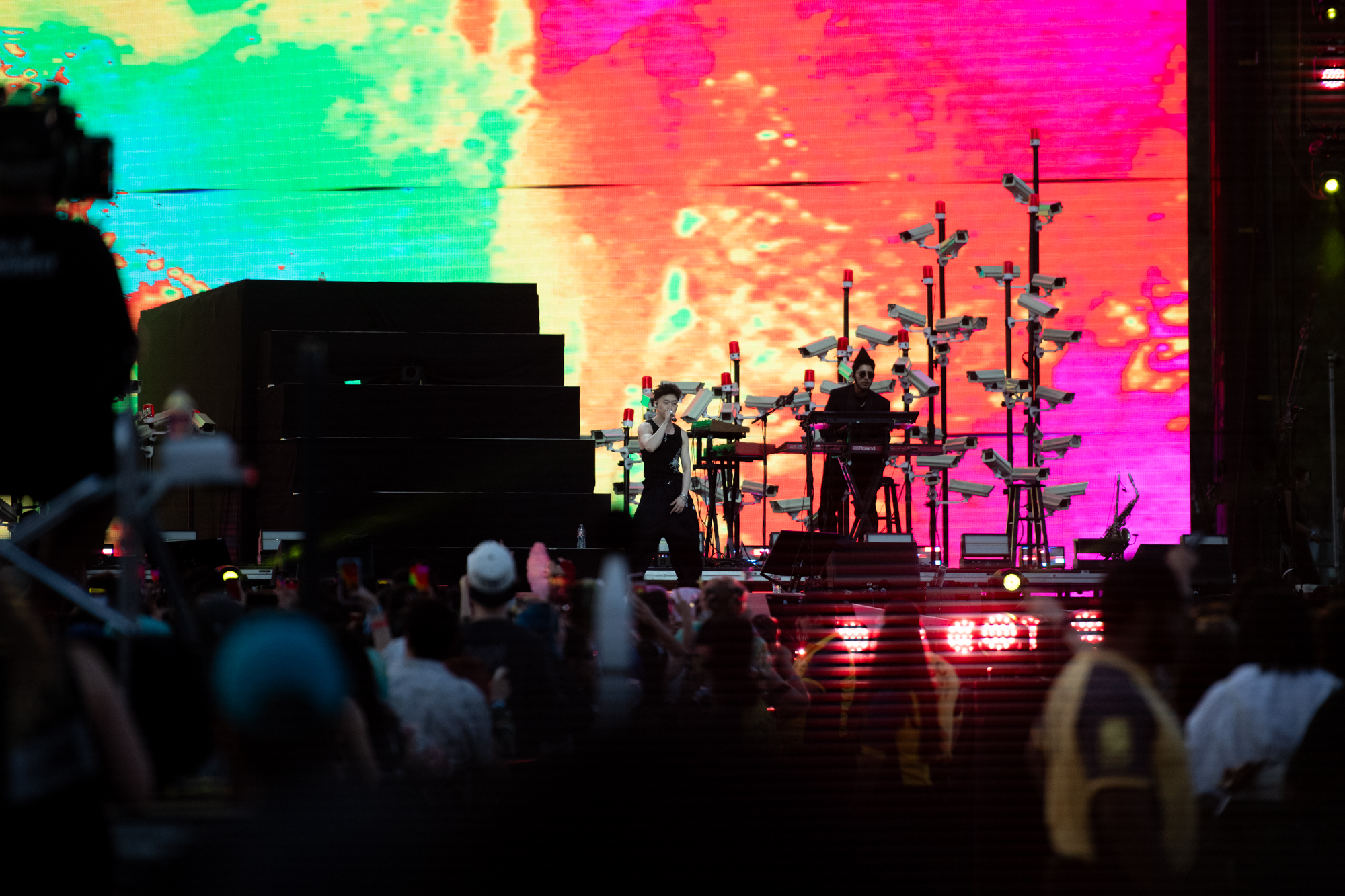 Rich Brian performs on stage at the first day of the 2025 Head in the Clouds Music & Arts Festival in Pasadena, California while in front of a multicolor neon-tinted screen projection. The Indonesian rapper&squot;s setlist included songs such as "History," "Drive Safe" and "Butterfly." (Max Zhang/Daily Bruin)